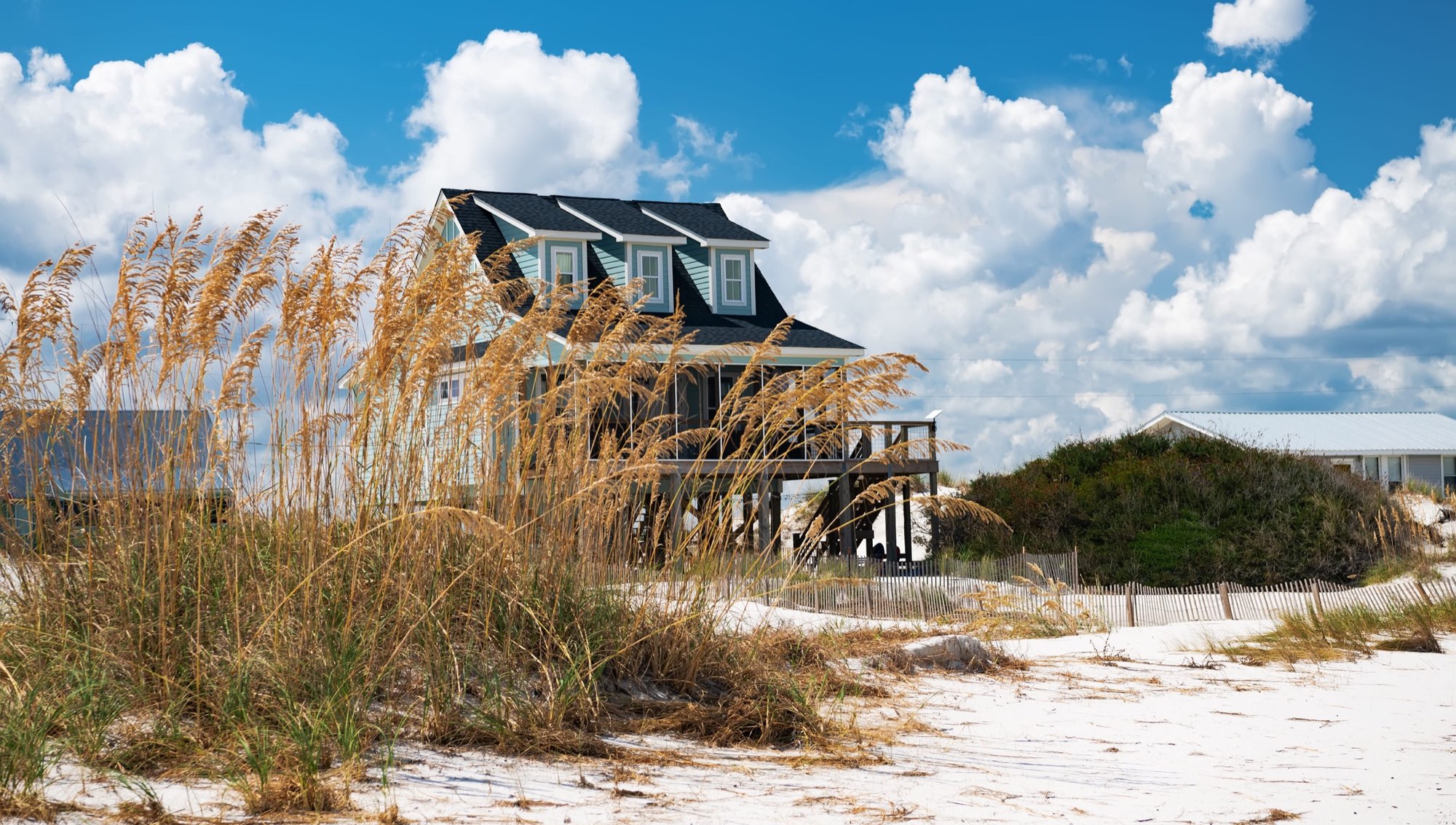 coastal beach house on stilts behind dune grass